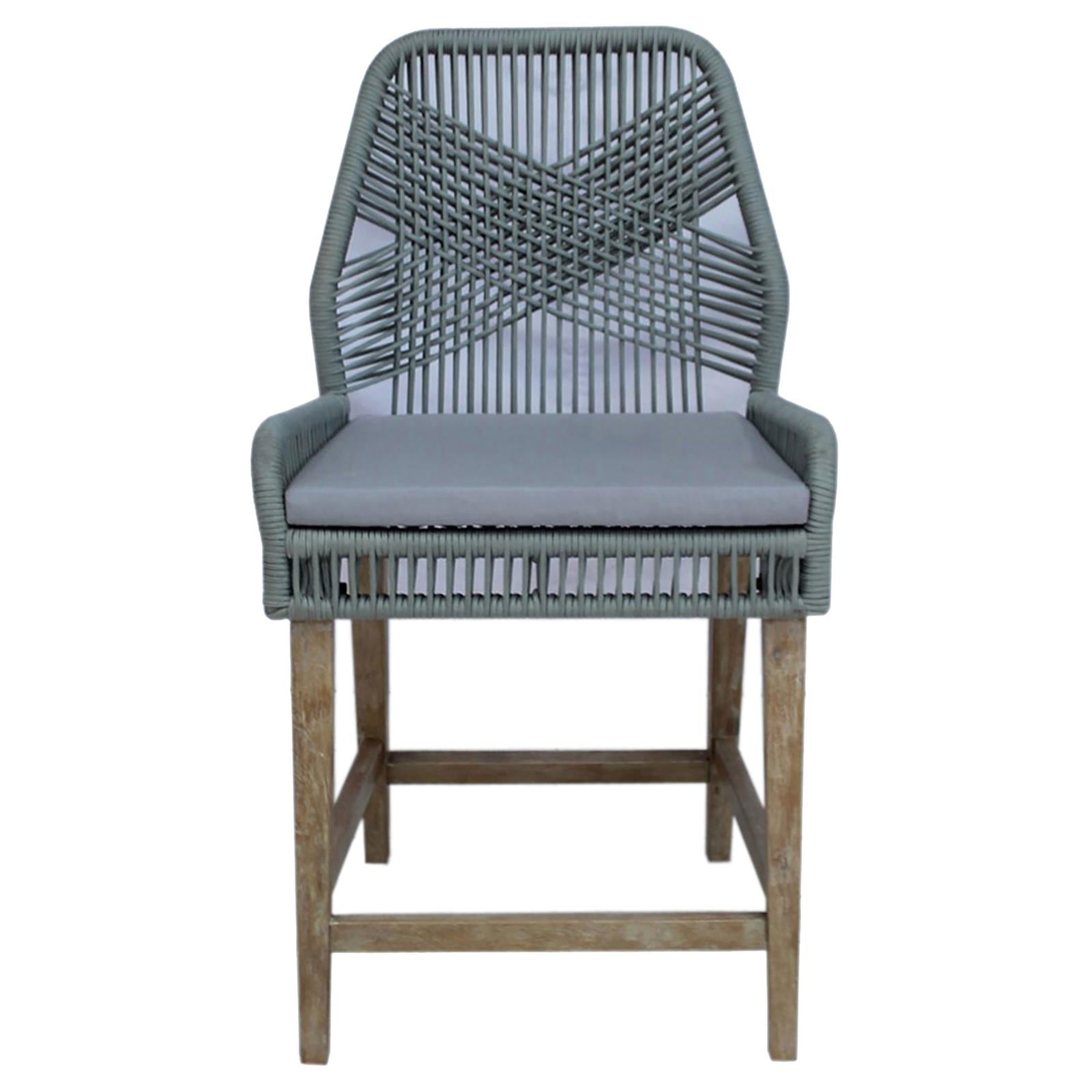 Sage green woven bar stool with gray cushion and distressed wood legs