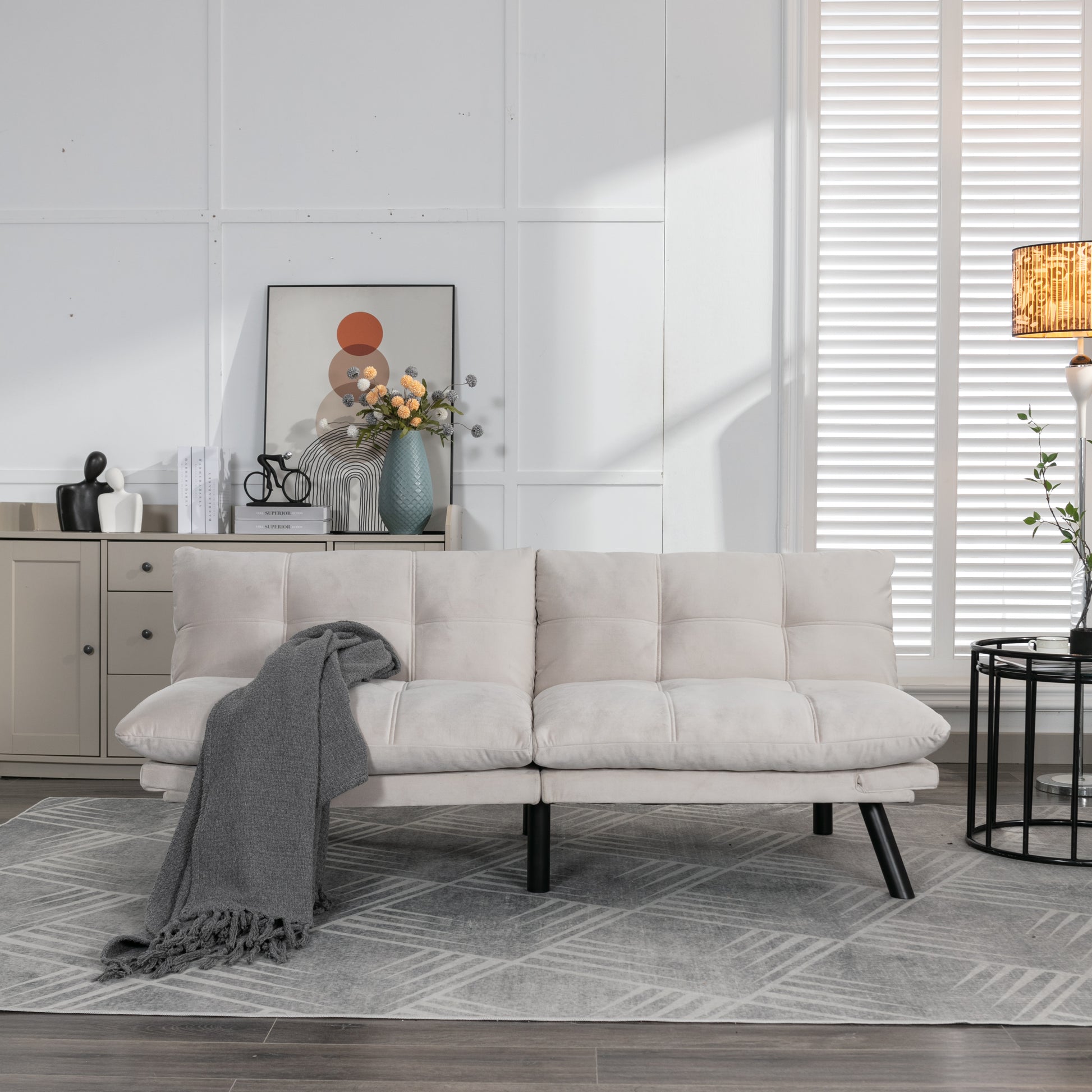 Cream velvet tufted sofa with a grey throw blanket and black legs