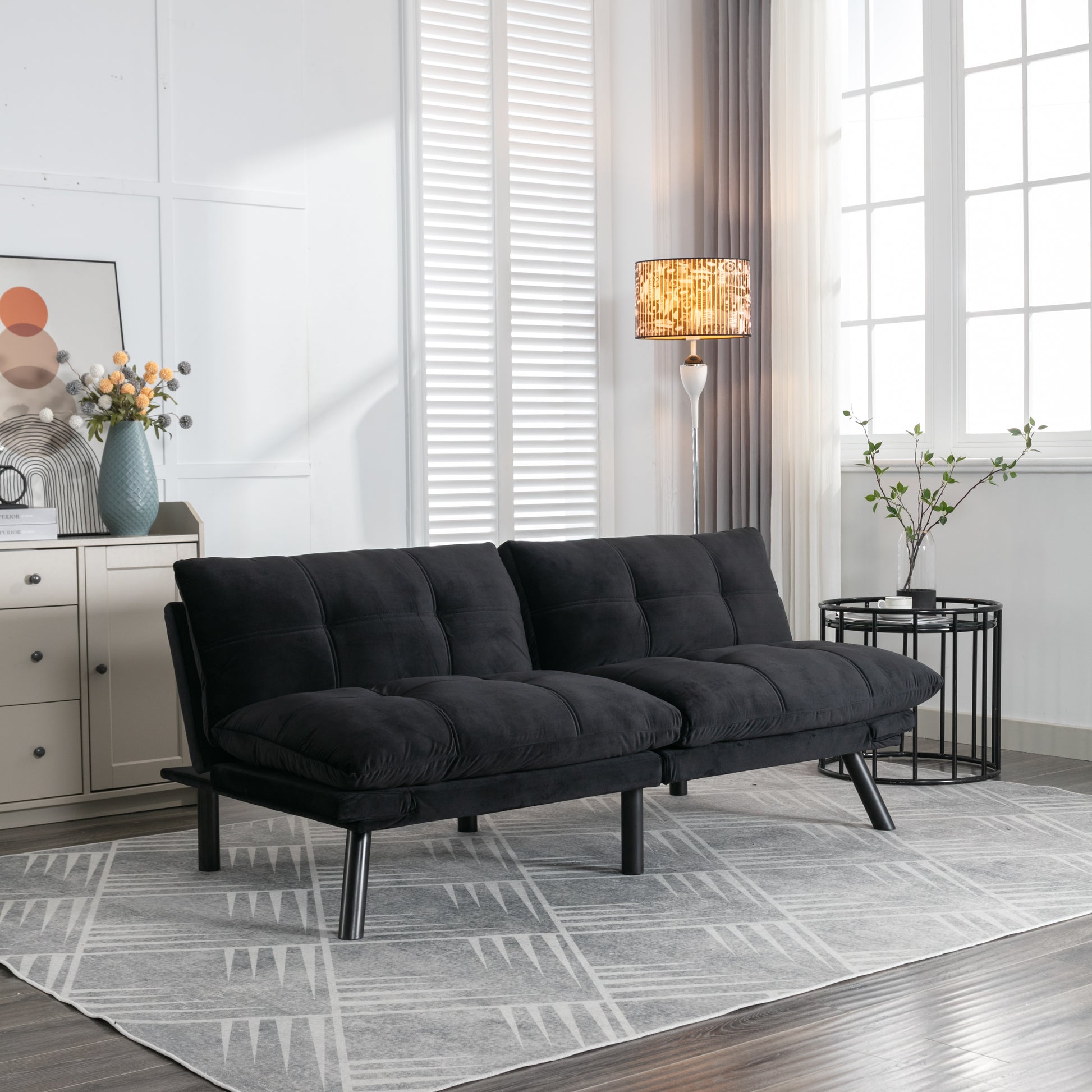 Black velvet futon sofa with tufted cushions and metal legs for modern living rooms