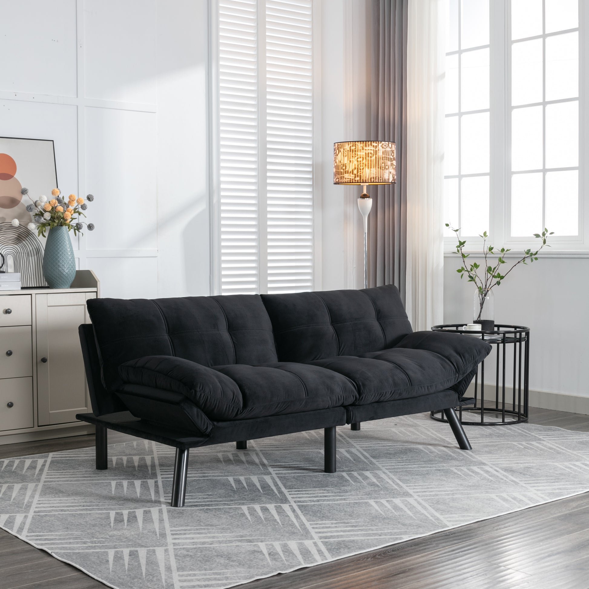 Black velvet futon sofa with tufted cushions and metal legs ideal for small apartments