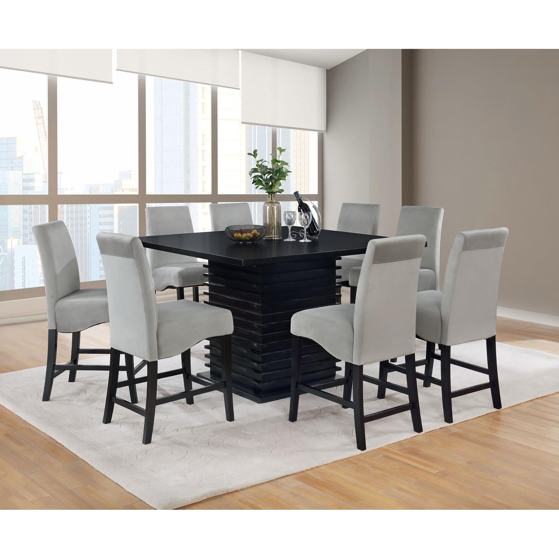 Modern square bar height table with tiered black base and eight light grey upholstered bar stools