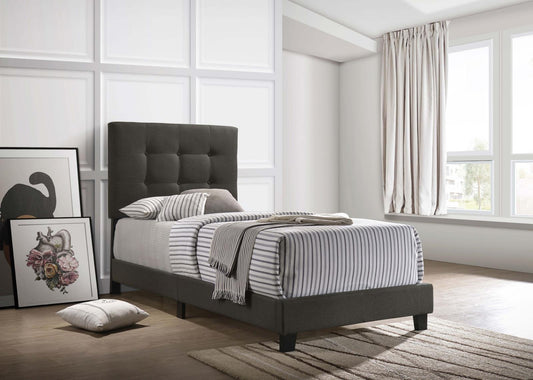 Dark grey upholstered twin bed with tufted headboard and striped bedding