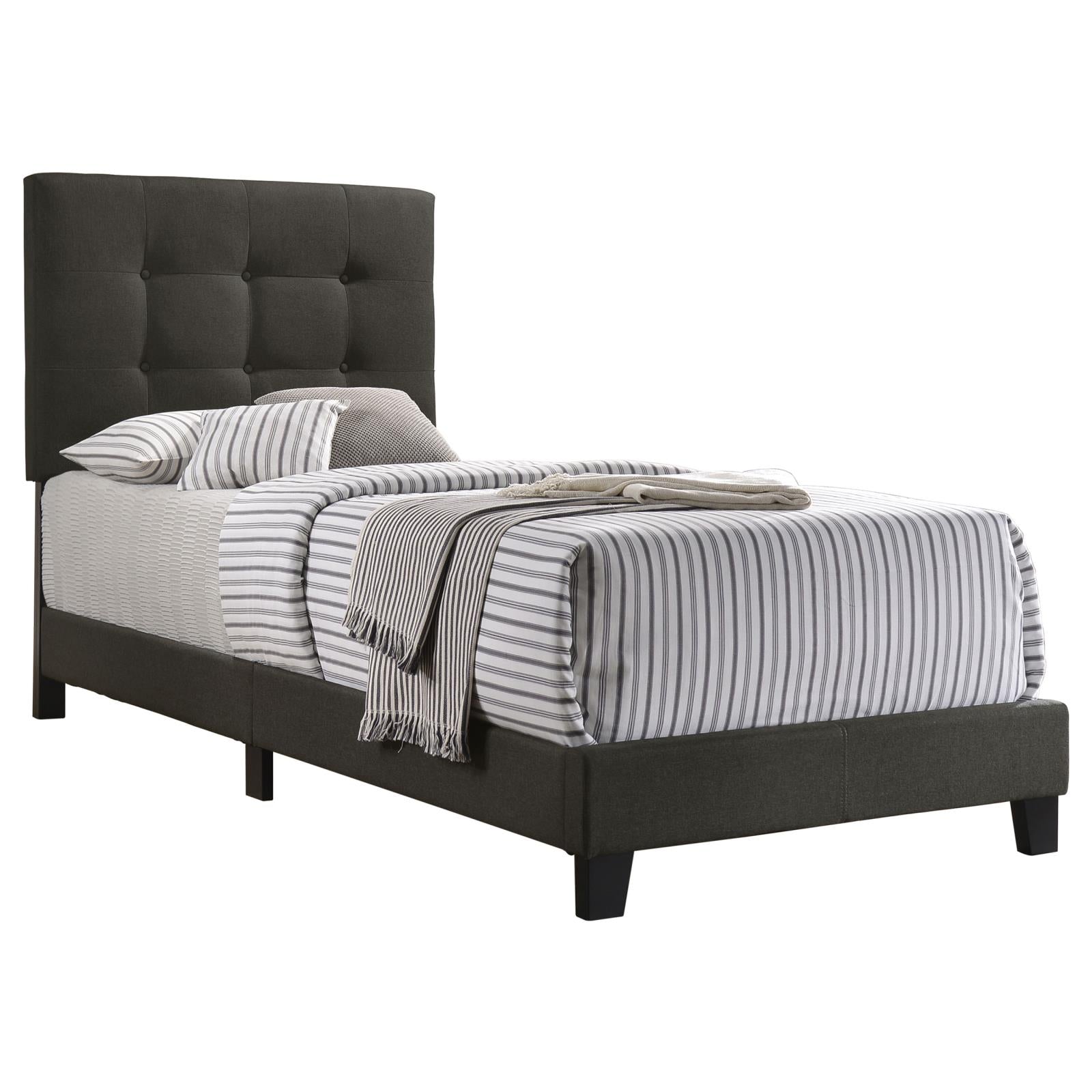 Dark gray tufted upholstered twin bed frame with striped bedding