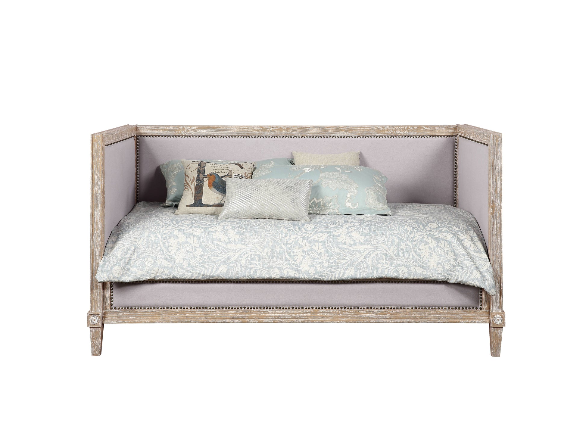 Light gray upholstered daybed with distressed wood frame and botanical print bedding