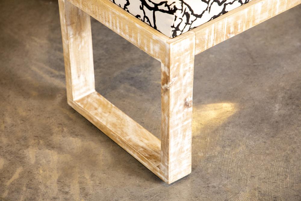 Distressed whitewashed wood bench frame with black and white patterned cushion detail