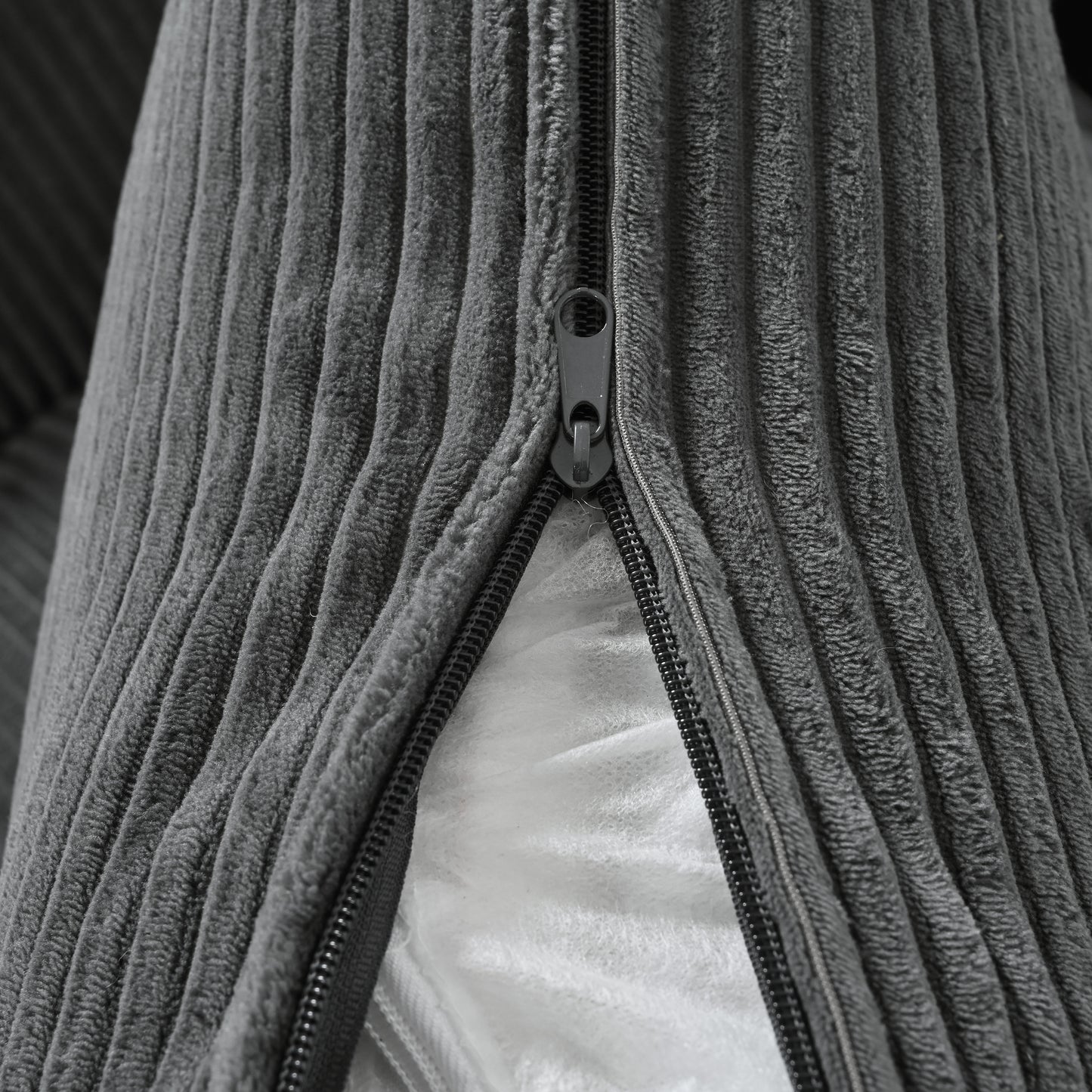 Closeup of grey corduroy fabric texture with a visible zipper on a cushion cover