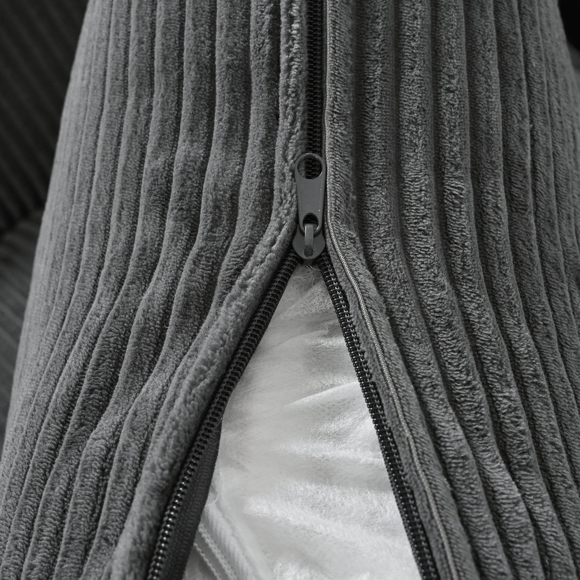 Closeup of grey corduroy fabric texture with a visible zipper on a cushion cover