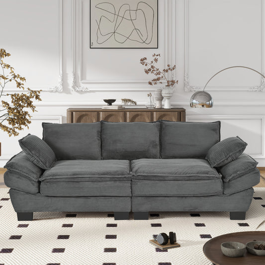 Plush grey corduroy threeseater sofa with deep seat cushions and oversized throw pillows
