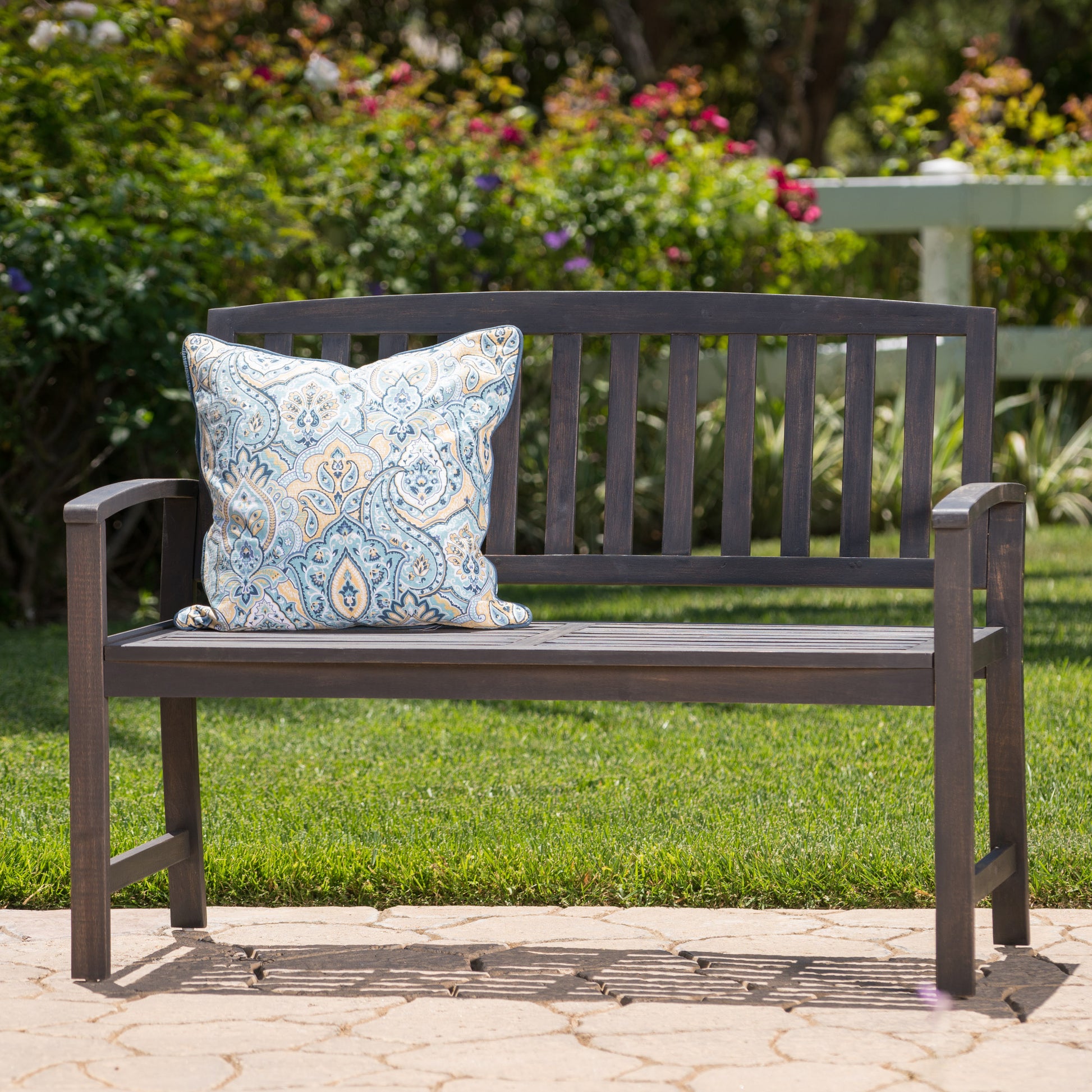 Dark brown wooden garden bench with a decorative outdoor cushion