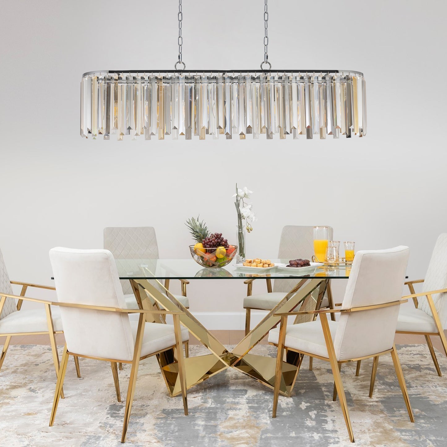 Rectangular crystal chandelier with chrome accents casting warm light over a dining set