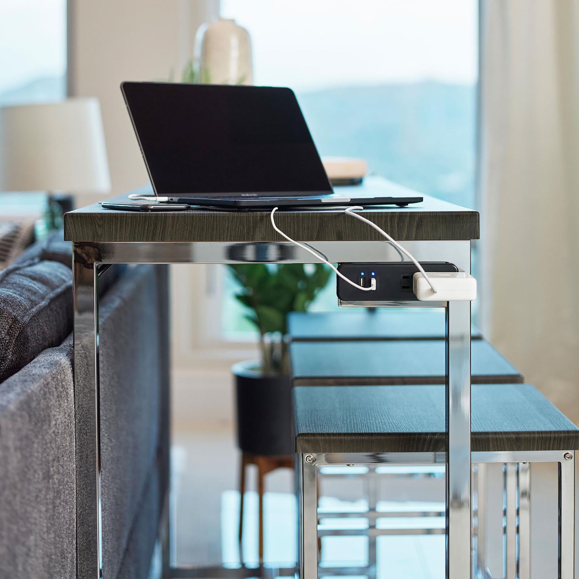 Dark wood and chrome console table with integrated power strip supporting a laptop