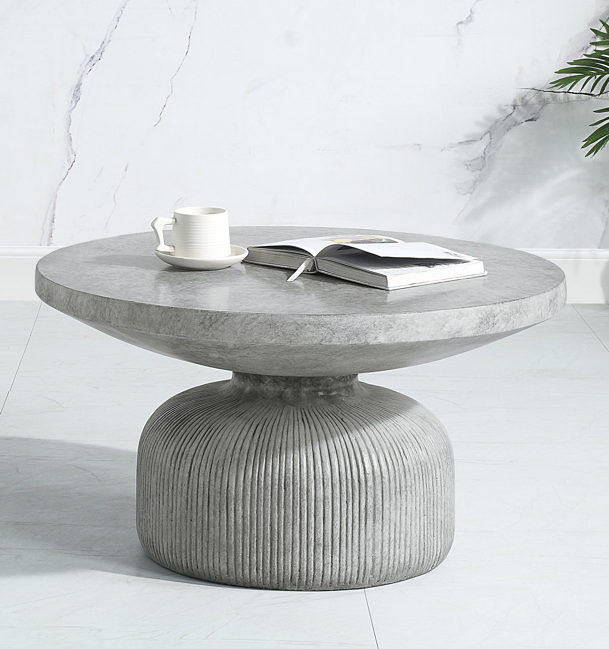 Round grey concrete coffee table with ribbed pedestal base and a book