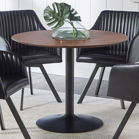 Round walnut dining table with ribbed black faux leather chairs