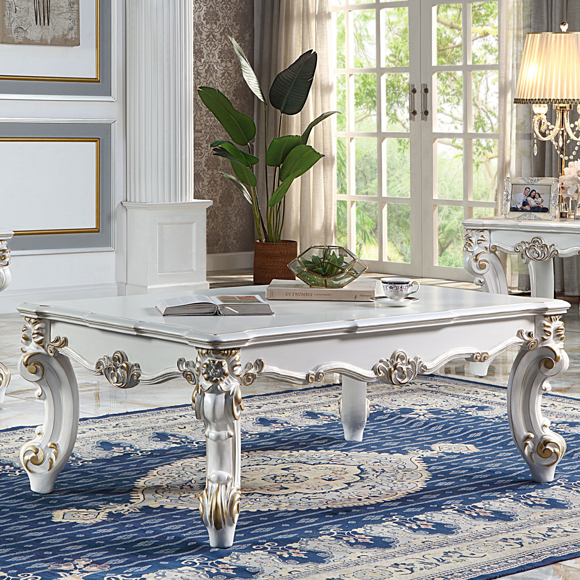 Ornate white and gold baroque coffee table with carved legs and a classic rug