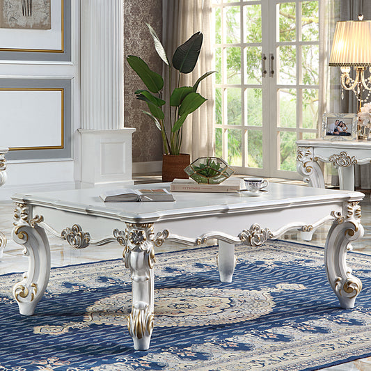 Ornate white and gold baroque coffee table with carved legs and a classic rug