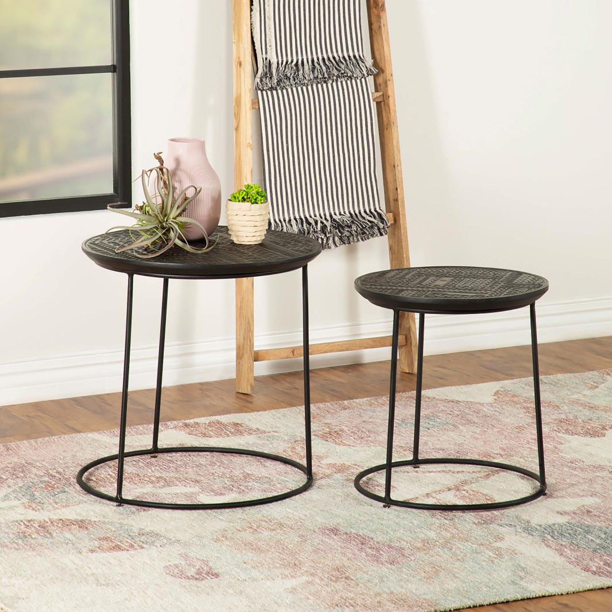 Two round black metal nesting tables with textured tops and slender legs