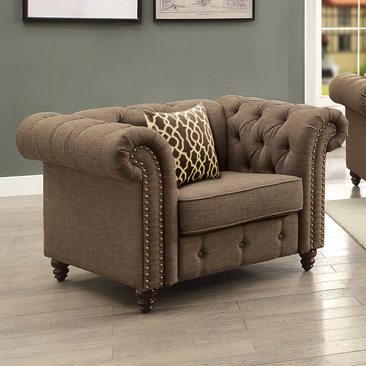 Brown fabric chesterfield armchair with button tufting and gold nailhead trim featuring a decorative pillow