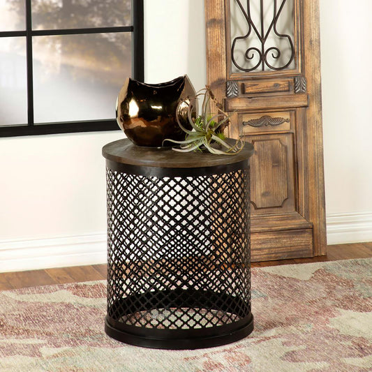 Black metal mesh accent table with rustic wood top holding decorative bowl