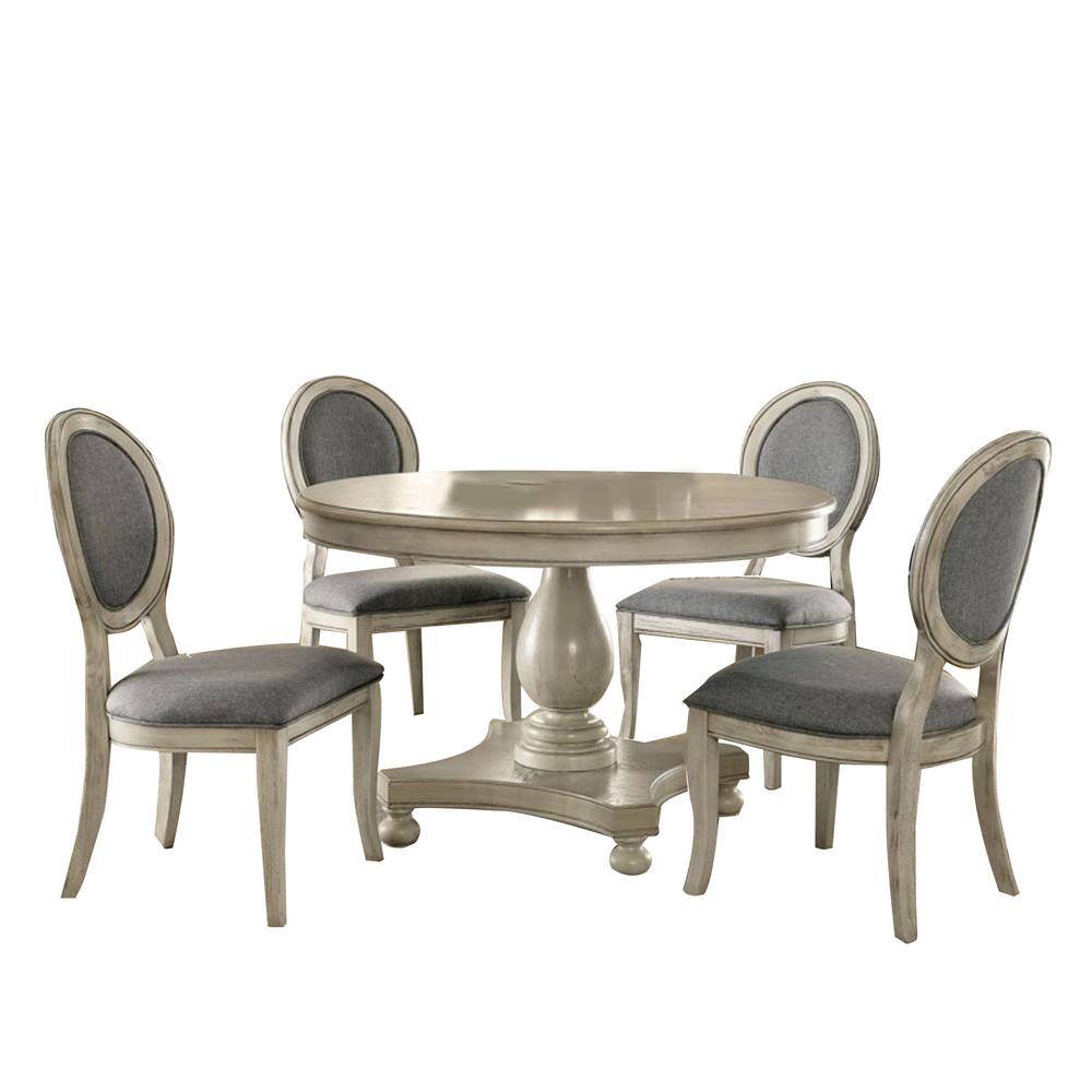 Elegant round dining table set with four upholstered chairs and pedestal base