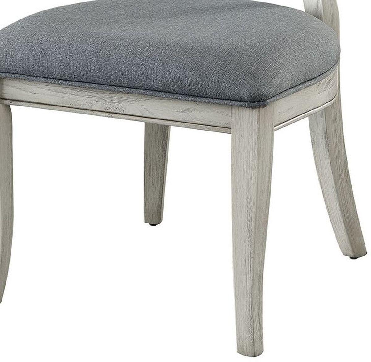 Close up of a grey upholstered dining chair with distressed white wooden legs