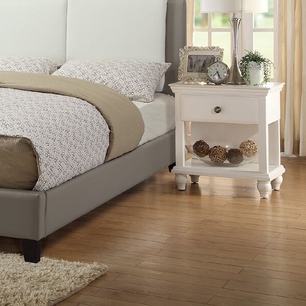 Grey upholstered bed frame with white tufted headboard and patterned bedding