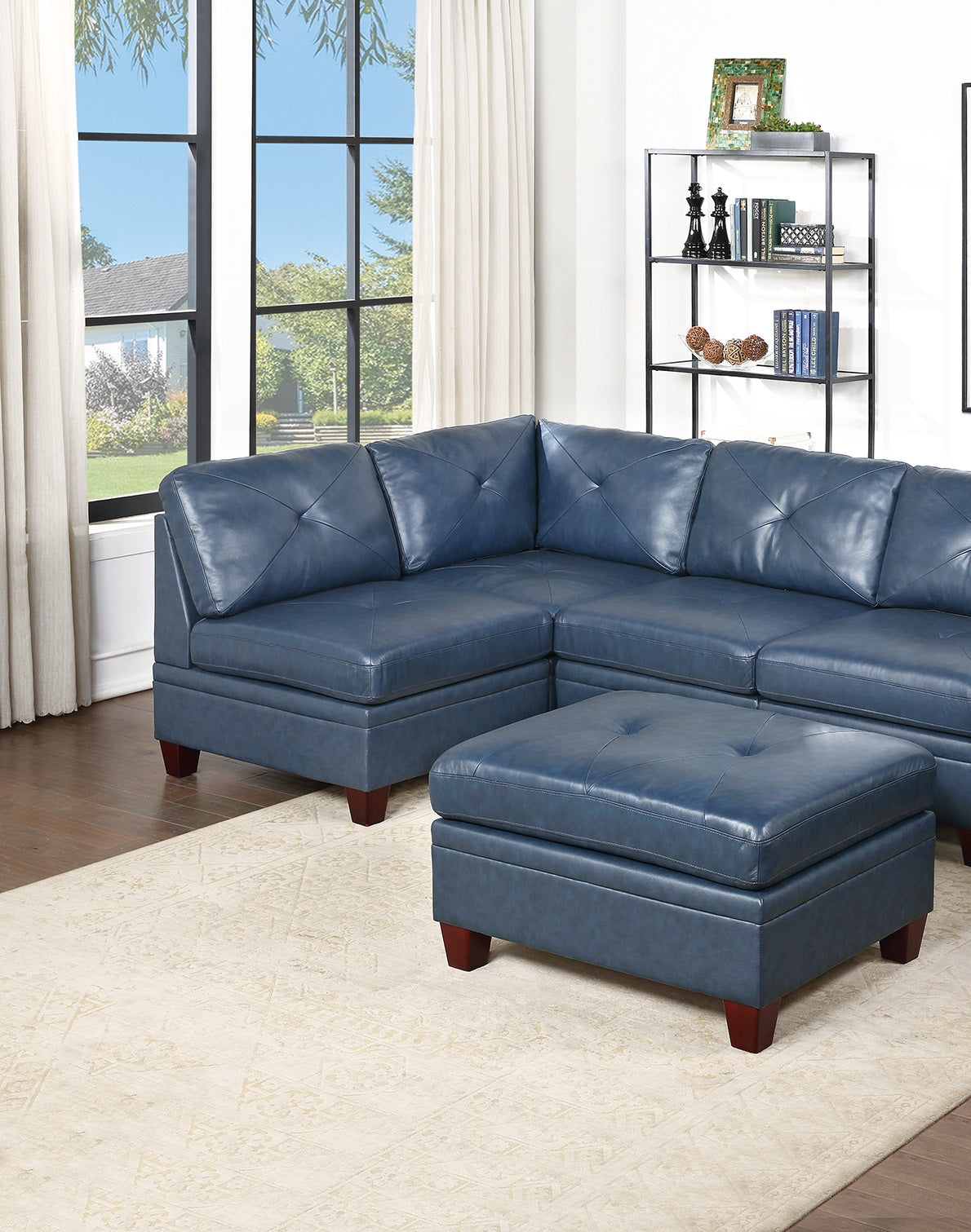 Blue tufted leather sectional sofa with matching ottoman in a living room setting