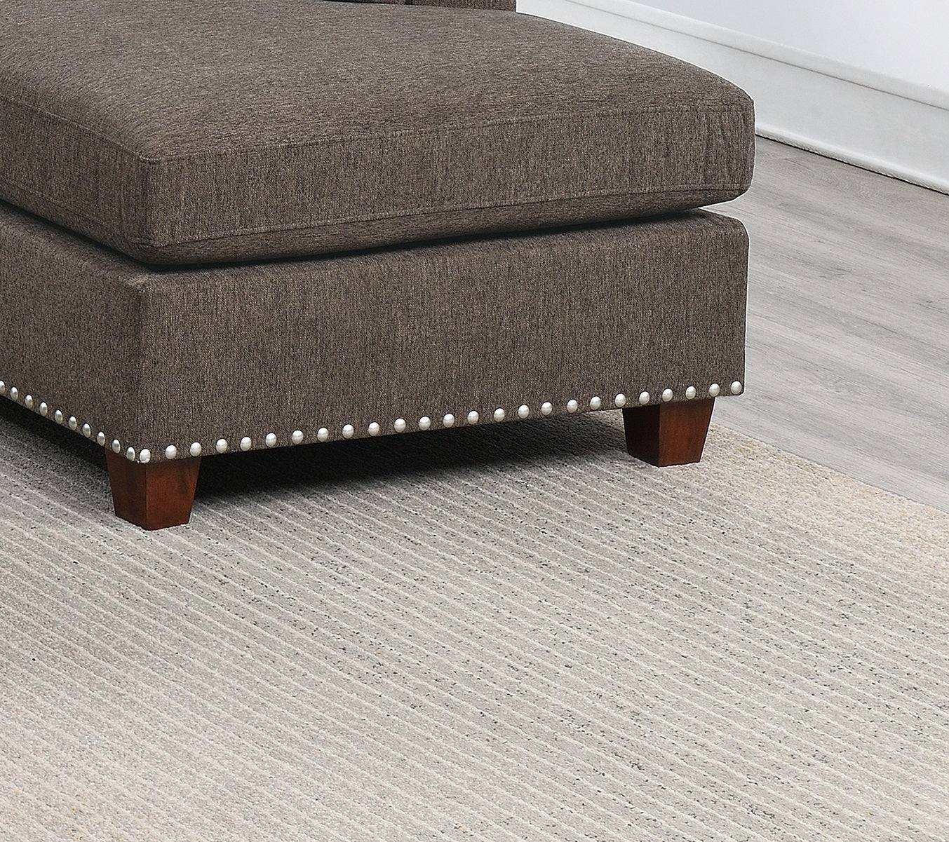 Dark brown fabric sectional with decorative nailhead trim and wooden legs