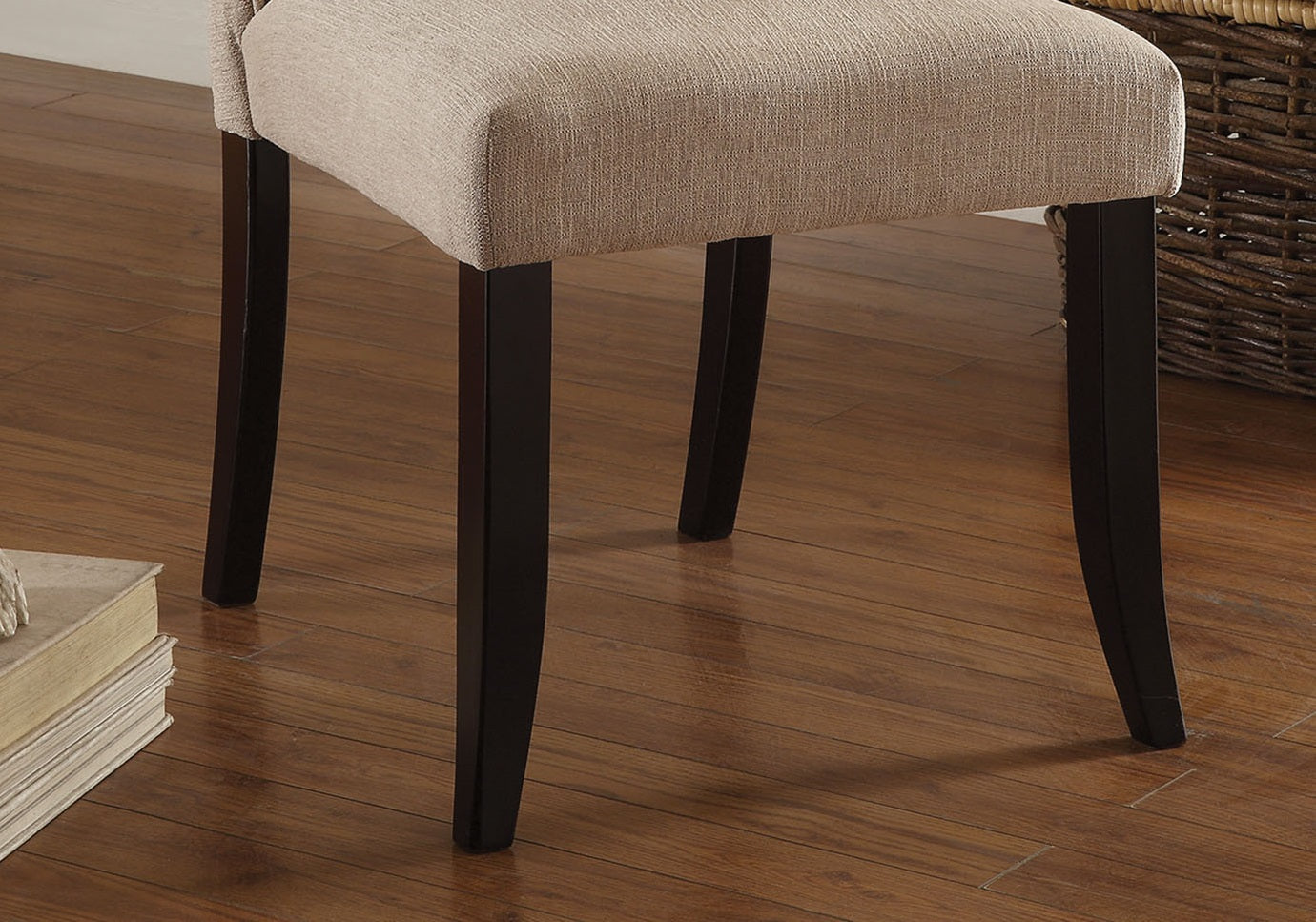 Upholstered dining chair in beige fabric with dark wood legs on hardwood floor