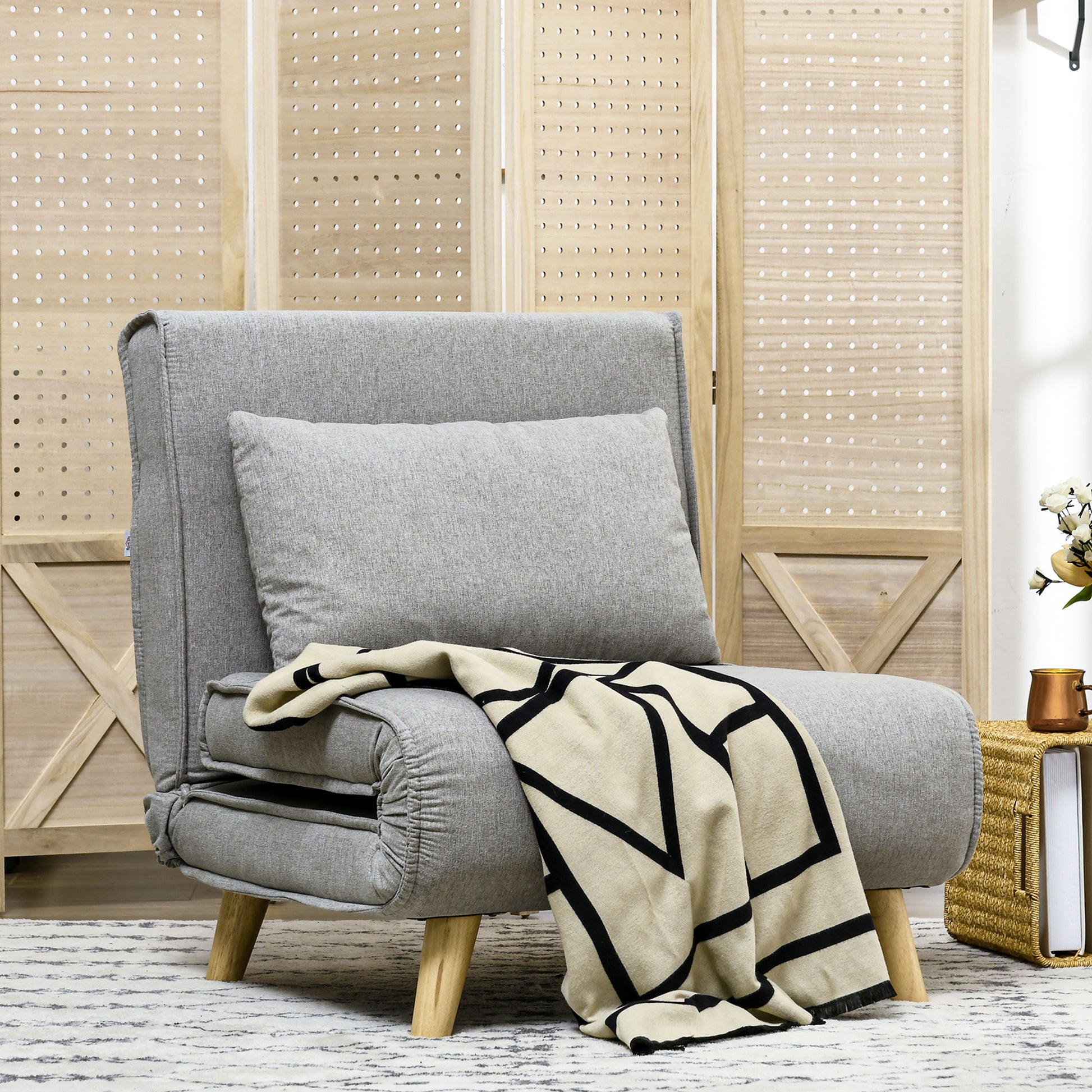 Gray upholstered convertible sofa bed with a black and cream geometric throw blanket