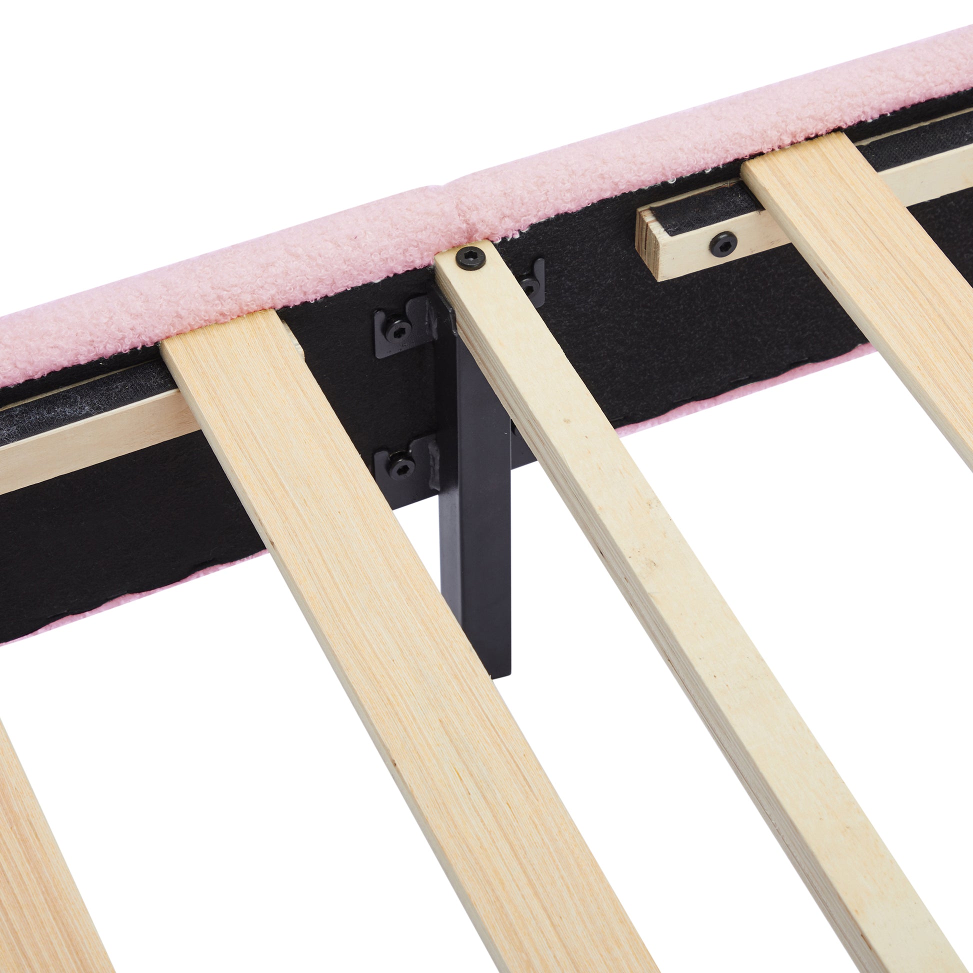 Closeup of a pink teddy fabric bed frame edge with wooden slats and black metal support