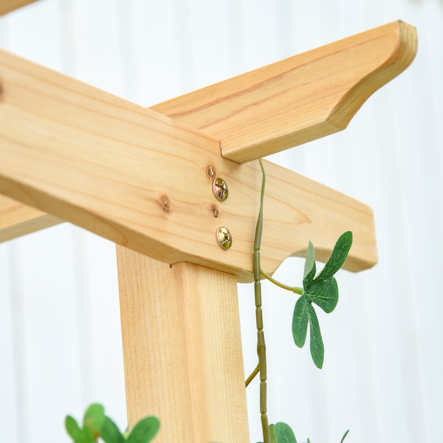 Closeup of light wood arbor construction with metal screws and green vine detail