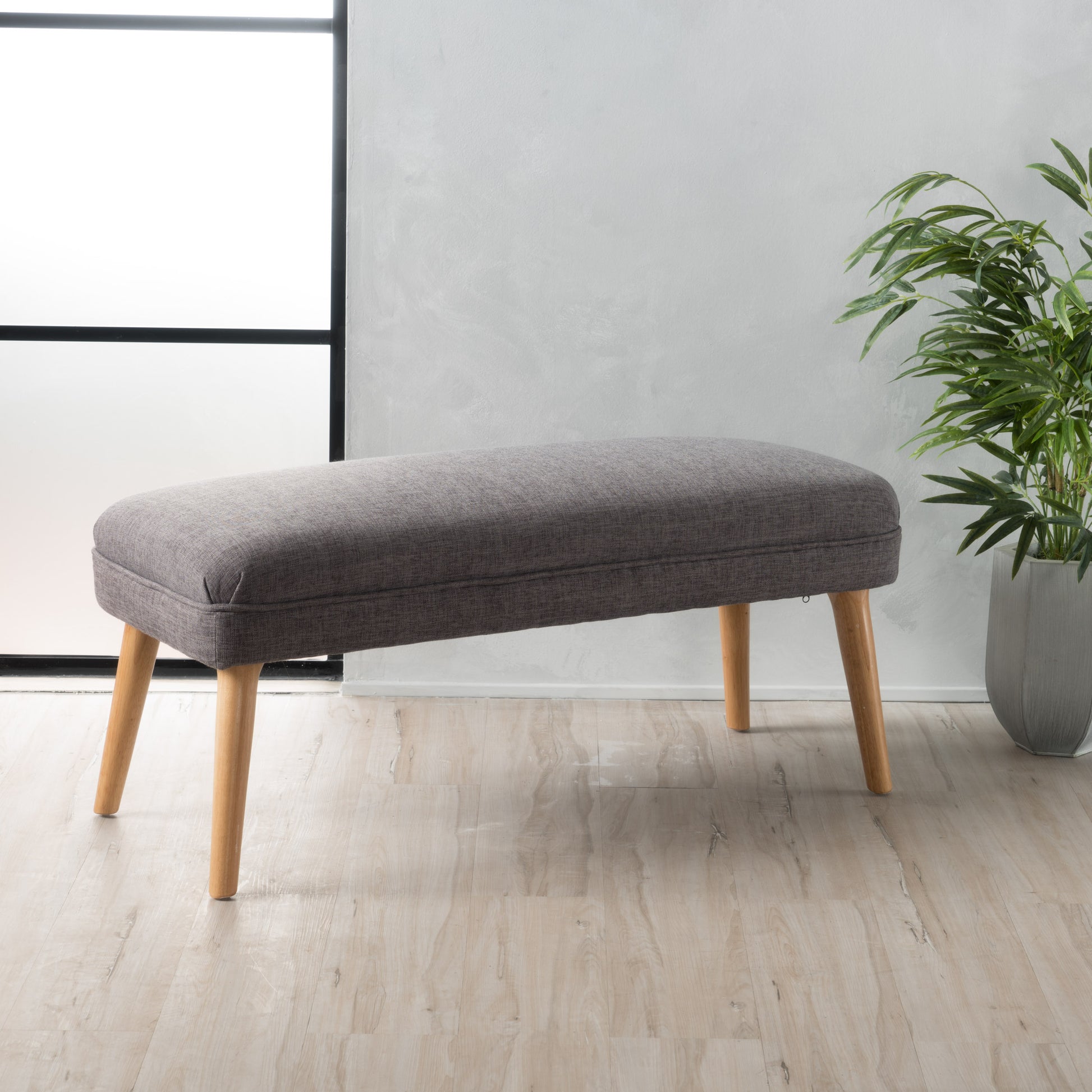 Tufted charcoal grey fabric bench with tapered wooden legs perfect for entryways