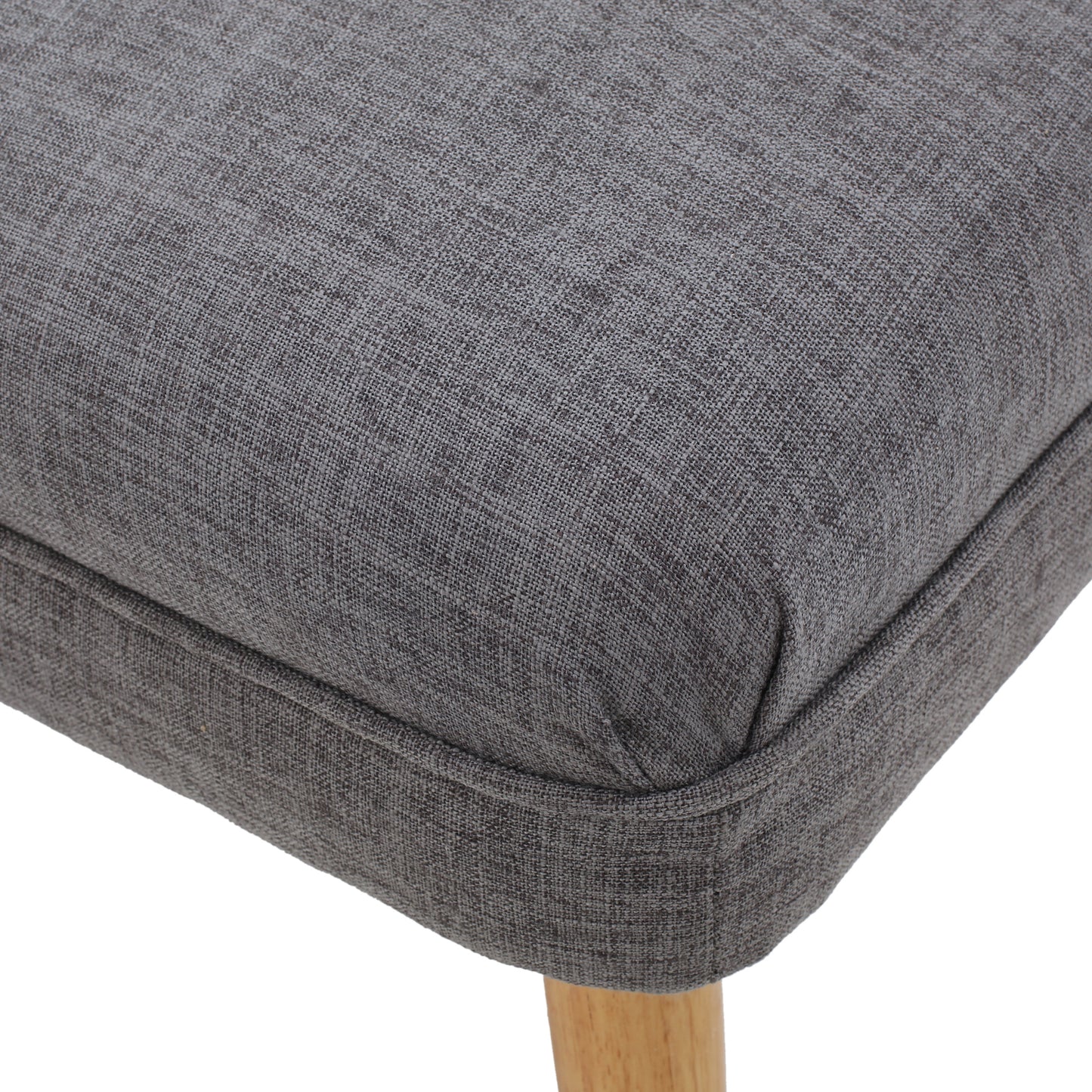 Closeup of a textured dark grey fabric dining chair seat with light wood legs