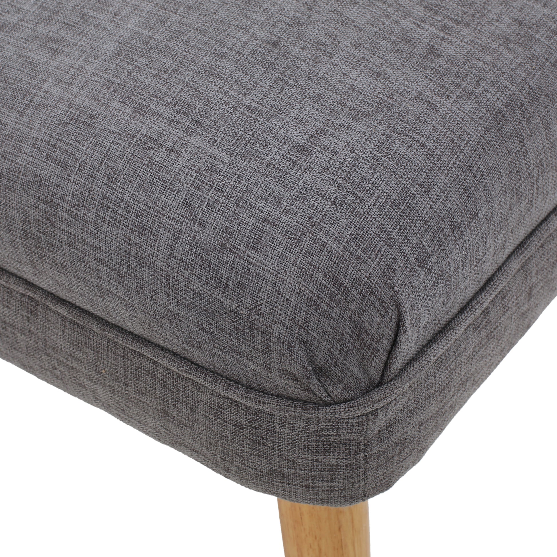 Closeup of a textured dark grey fabric dining chair seat with light wood legs