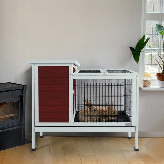 Two rabbits rest in a spacious white wooden rabbit hutch with a red wood panel enclosure