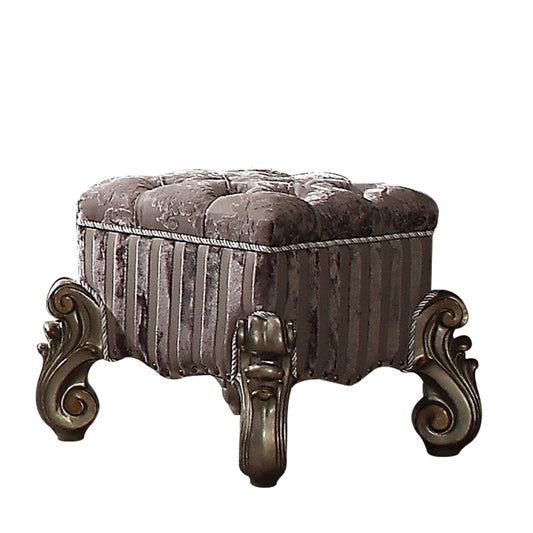 Ornate tufted velvet ottoman in grey with decorative carved legs and striped fabric sides