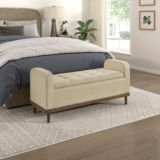 Beige tufted storage bench with dark wood legs in a bedroom setting