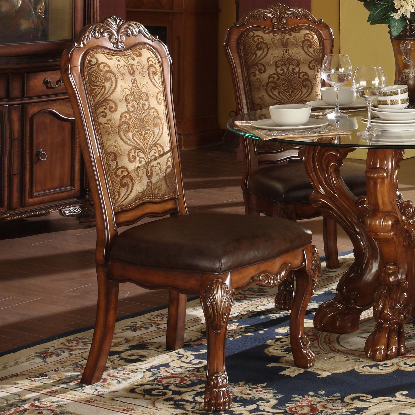 Ornate carved wood dining chair with patterned gold fabric back and brown leather seat