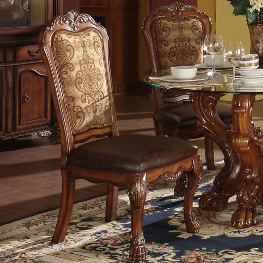 Ornate carved wood dining chair with patterned gold fabric back and brown leather seat