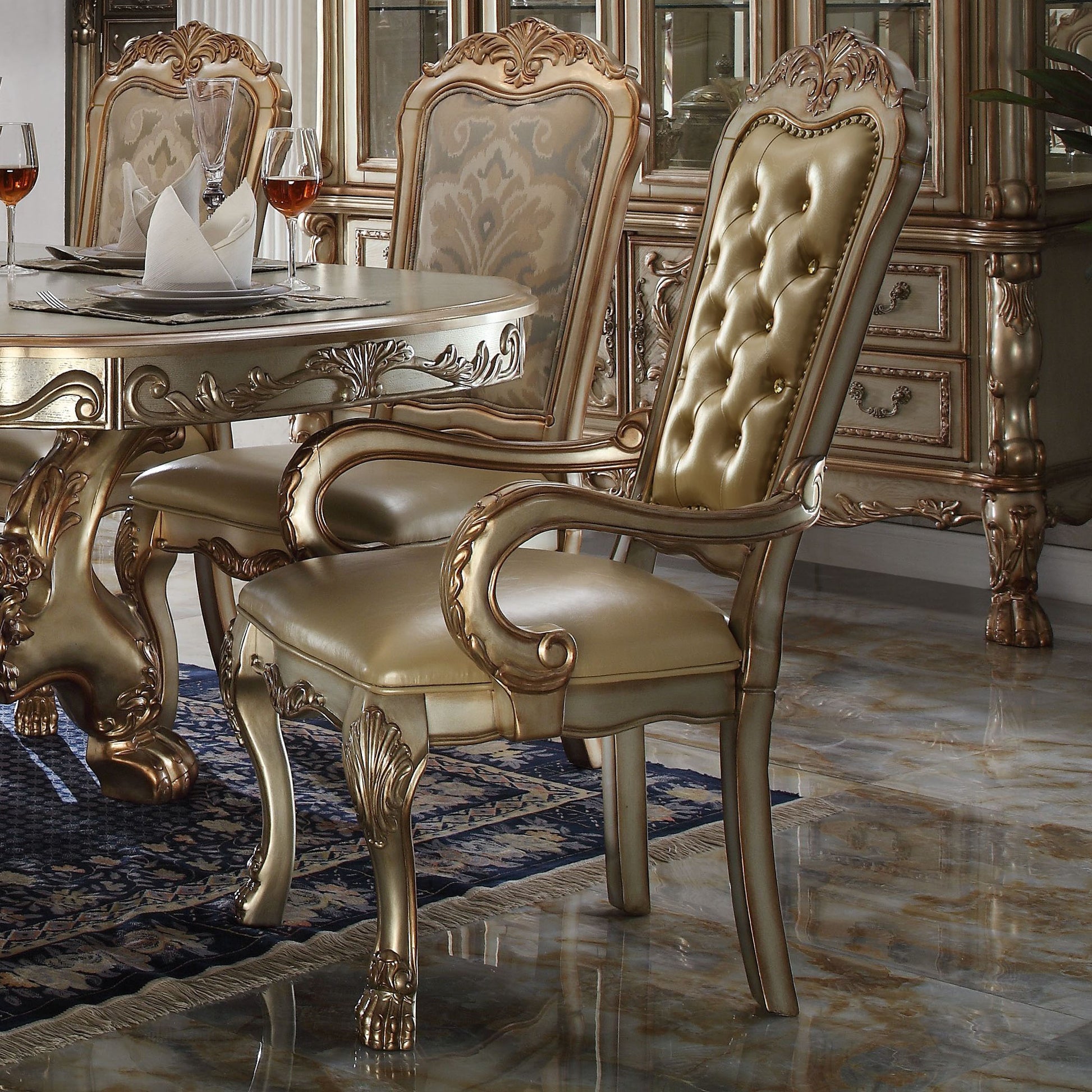 Ornate gold dining chair with tufted champagne leather upholstery and carved wood accents