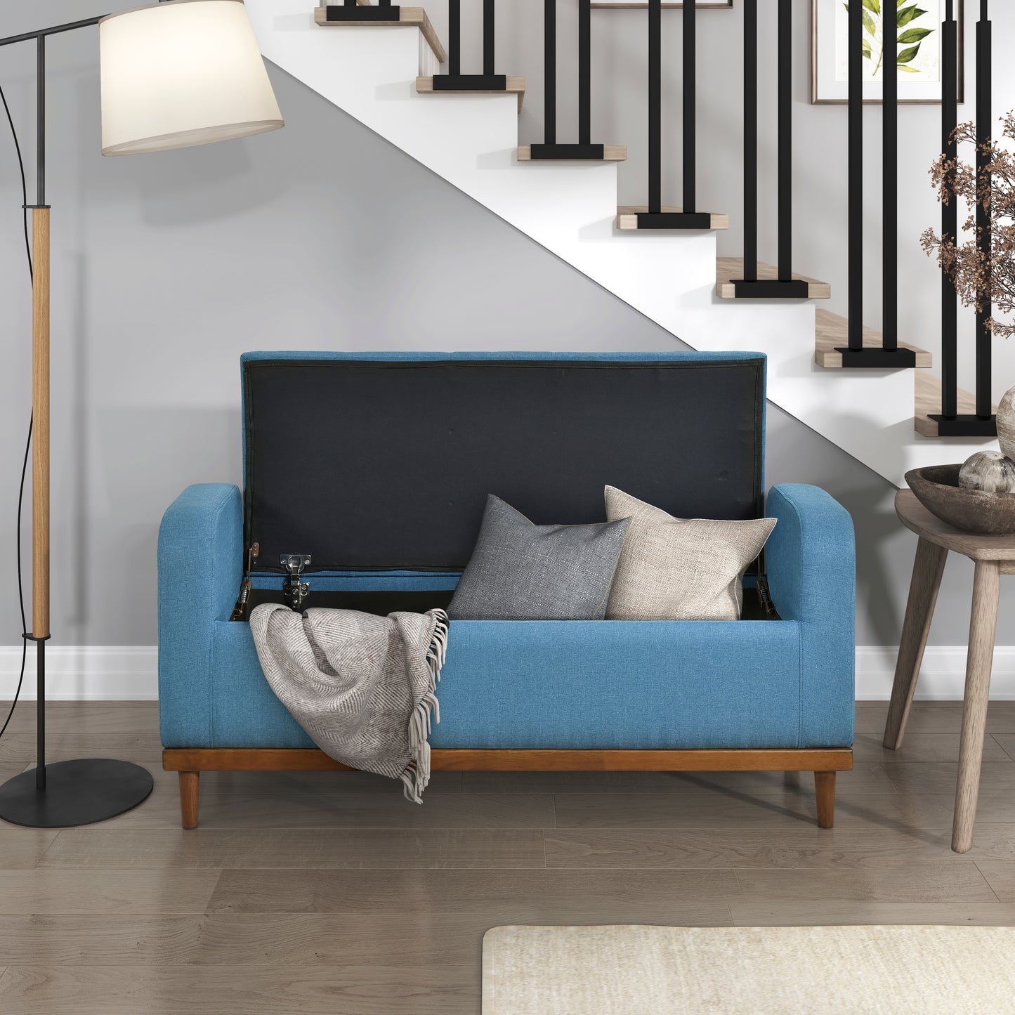 Blue upholstered storage bench with open lid revealing cushions and blanket