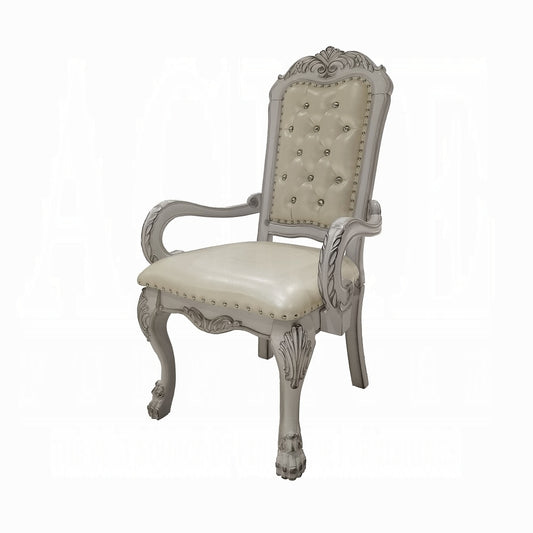 Ornate carved silver dining chair with tufted cream upholstery