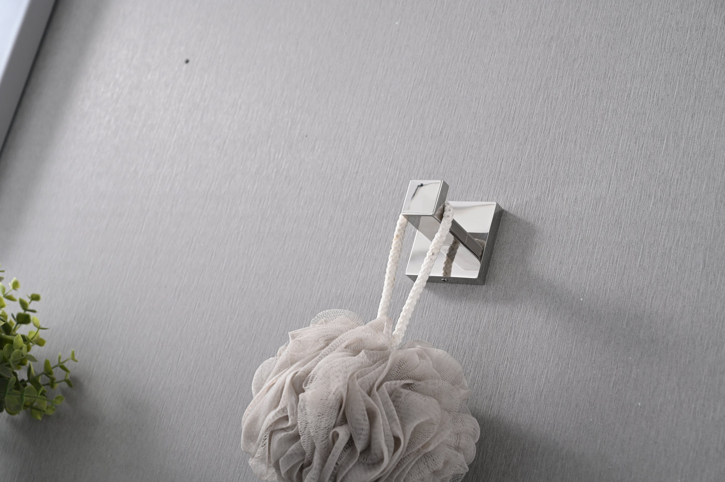 Modern chrome bath hook holding a fluffy beige loofah with a white rope