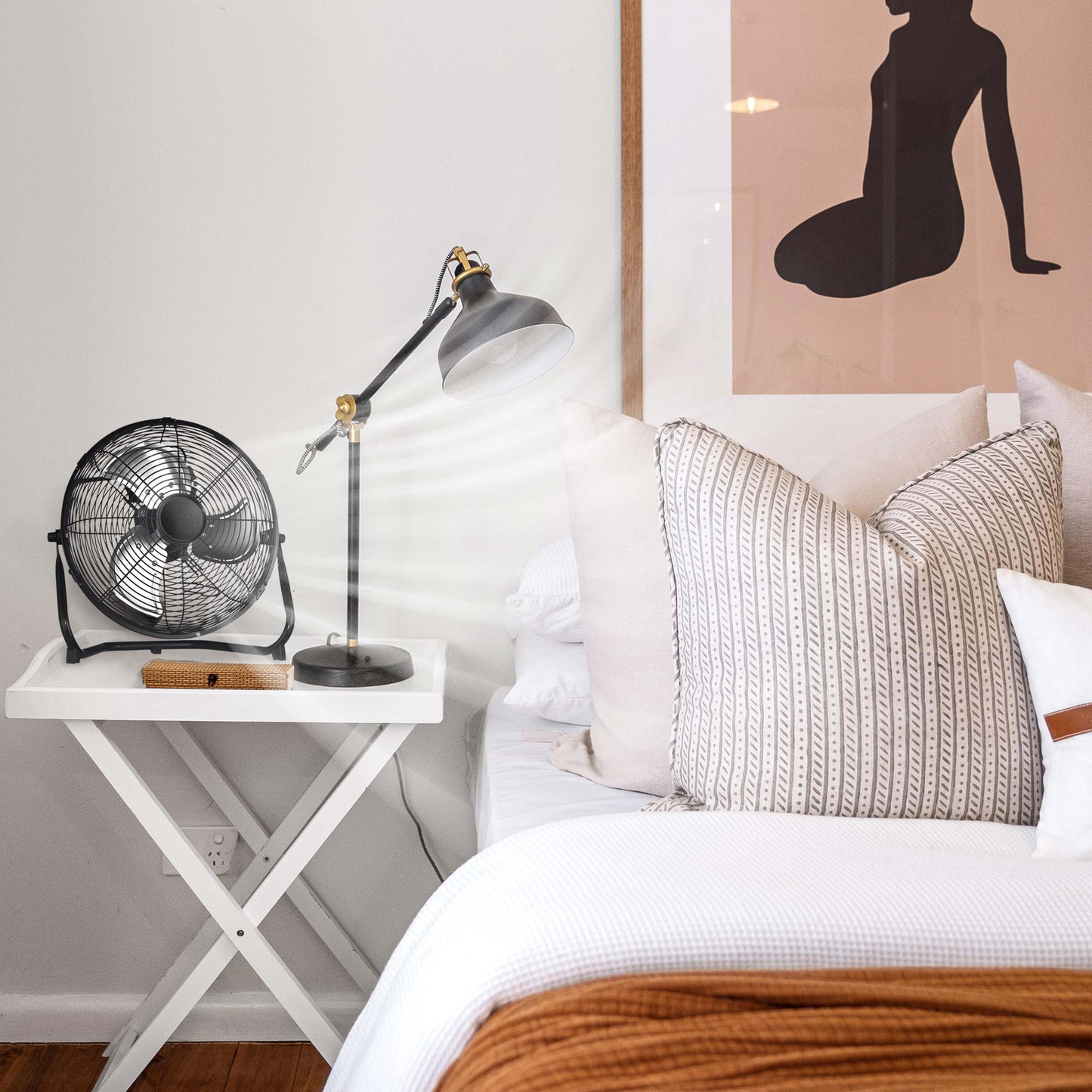 Black oscillating desk fan with metal grill and base on a white tray table