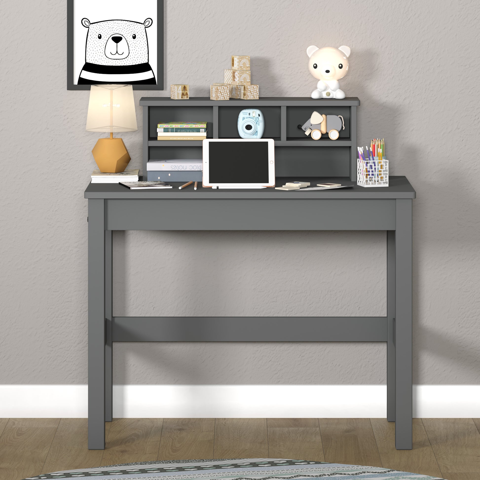 Gray wooden kids desk with organized shelves holding books and tablet