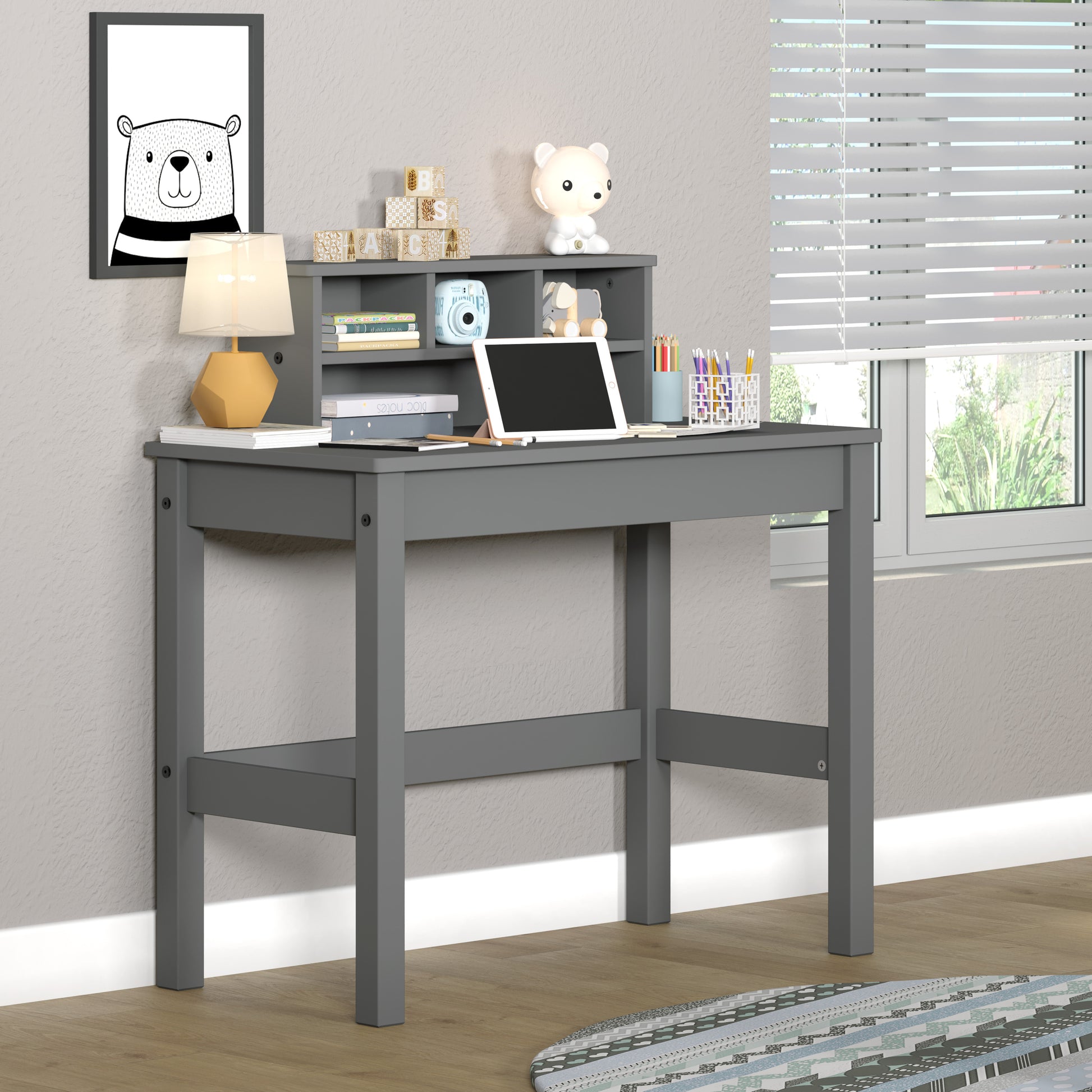 Gray wooden childrens desk with storage hutch and tablet on top