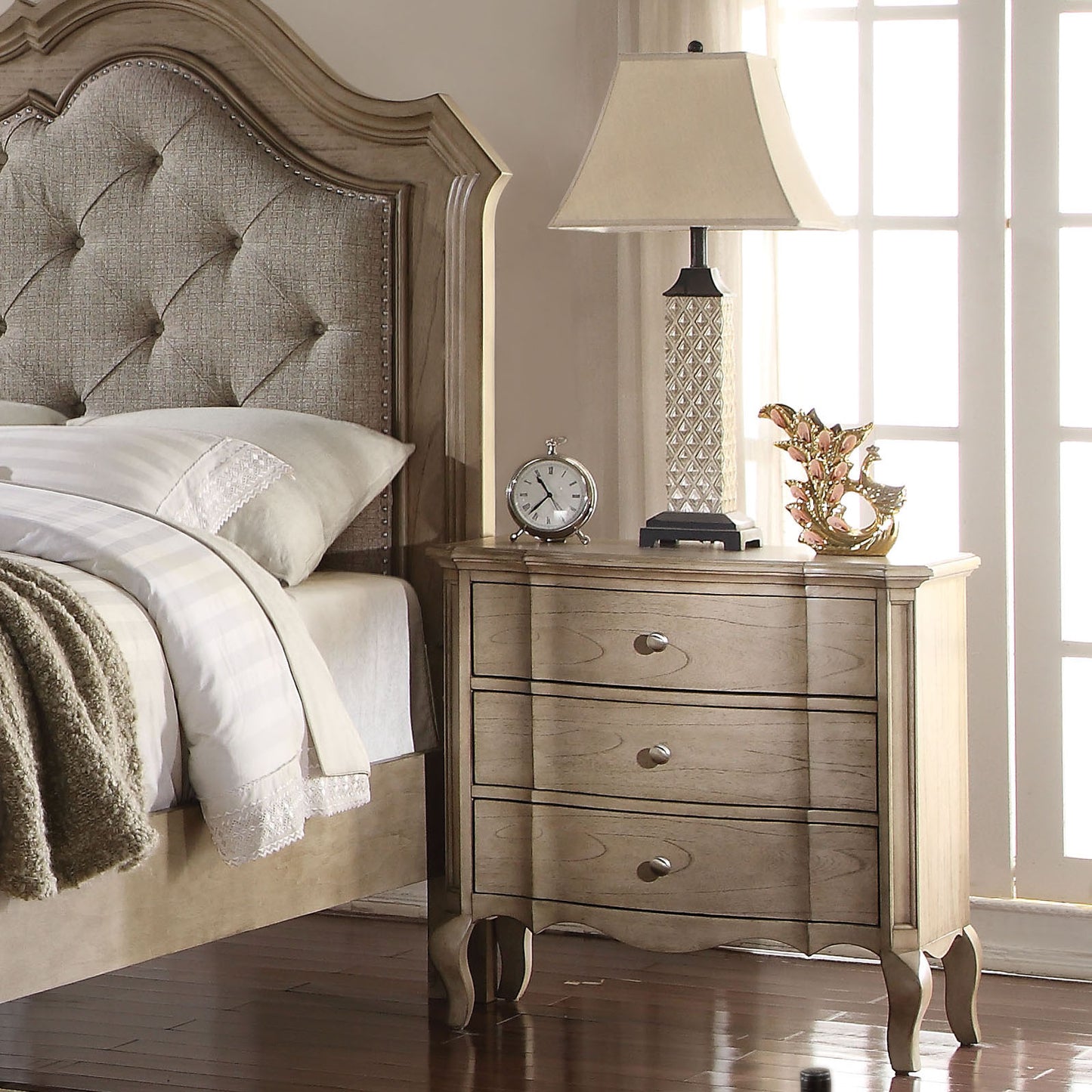 Threedrawer wooden nightstand with silver pulls complementing a classic bedroom set