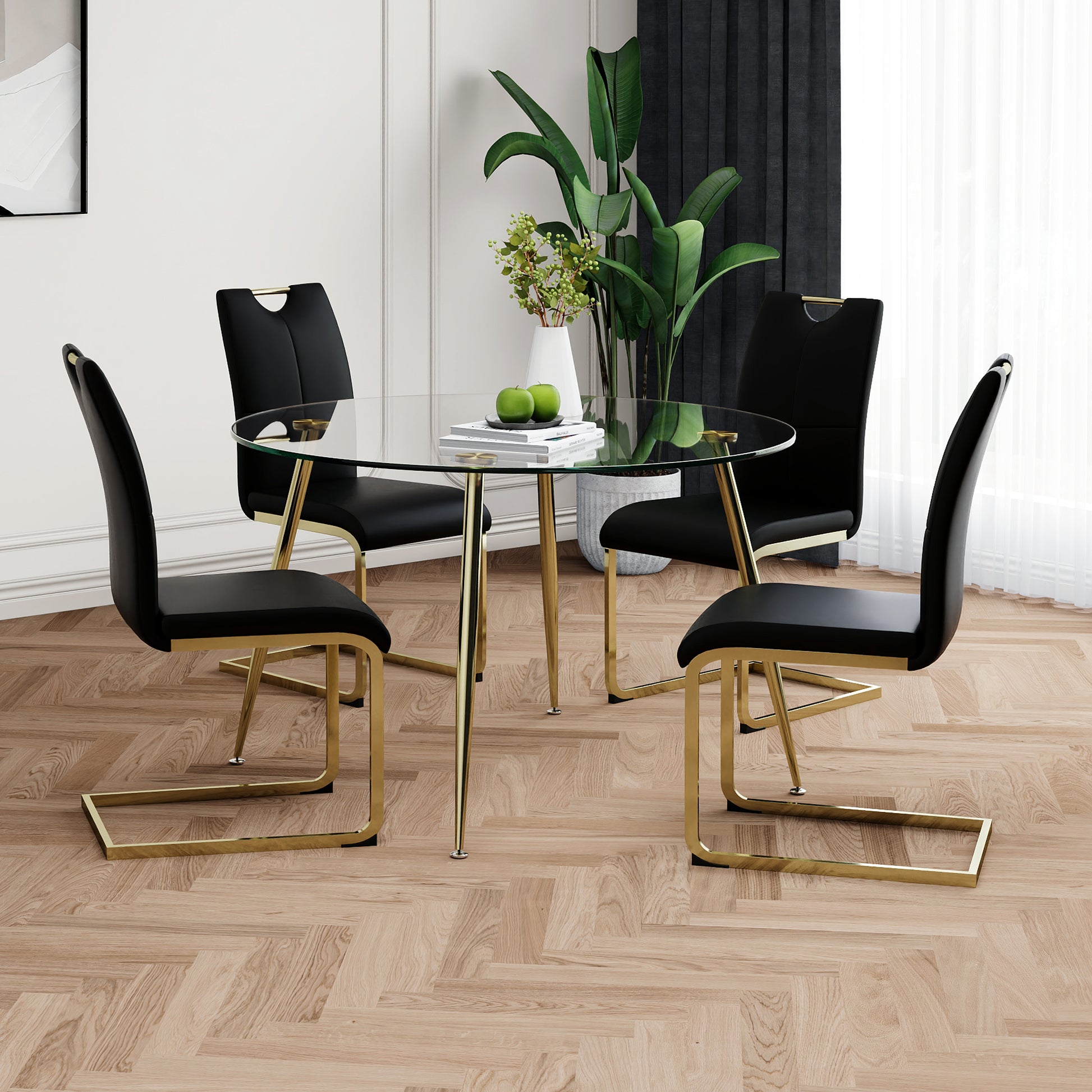 Round glass dining table with four black velvet chairs and gold accents