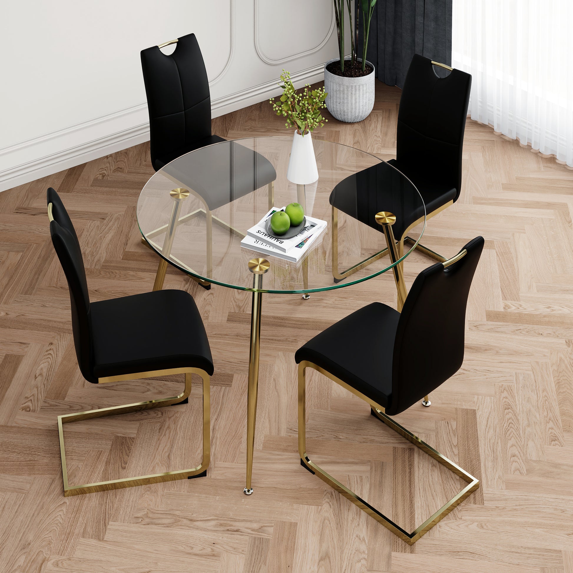 Round glass dining table with four black chairs featuring gold frames