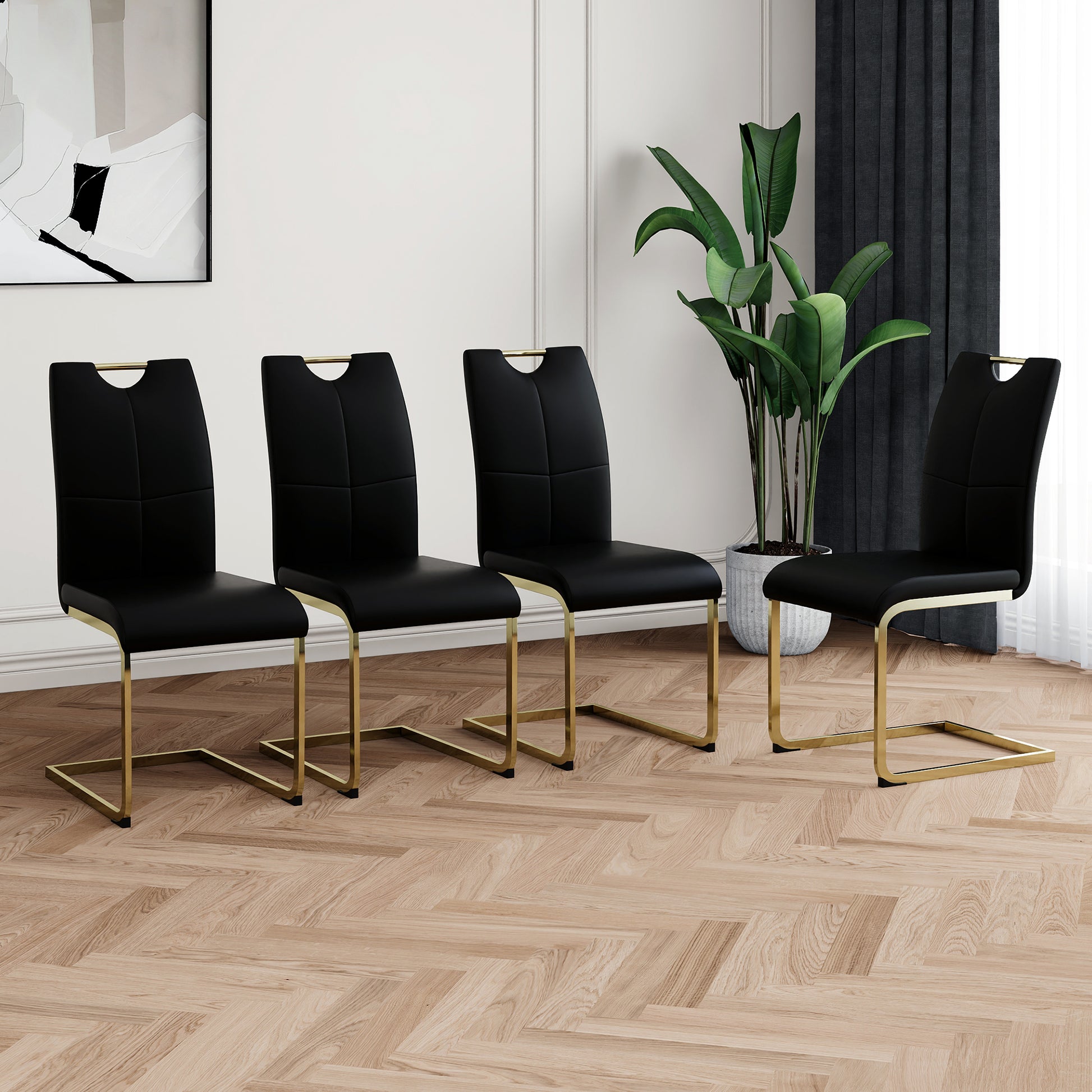 Four black leather dining chairs with gold metal legs and a cutout handle design